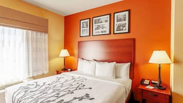A hotel room with a large bed, two bedside tables with lamps, a wooden headboard, and three framed pictures on the wall.
