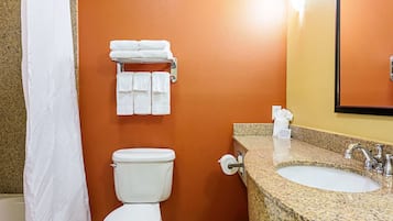 A bathroom with a white toilet, a sink with a granite countertop, and a towel rack with folded towels.