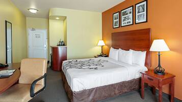 A hotel room with a bed, bedside lamps, a desk with a chair, and a dresser.