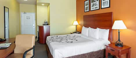 A hotel room with a bed, bedside lamps, a desk with a chair, and a dresser.