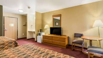 Une chambre d’hôtel équipée d’un lit, d’un bureau, d’une chaise, d’une télévision, d’une lampe et d’un petit réfrigérateur.