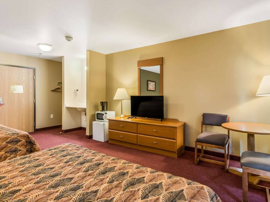 Une chambre d’hôtel équipée d’un lit, d’un bureau, d’une chaise, d’une télévision, d’une lampe et d’un petit réfrigérateur.