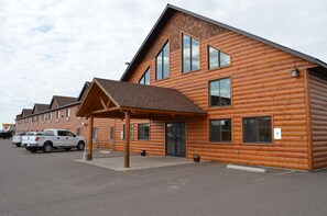 A log cabin-style building with a covered entrance, large windows, and a parking area with two white pickup trucks. - Econo Lodge Rice Lake (Rice Lake)