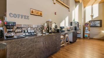 A modern coffee bar with a stone countertop, coffee machines, and a wooden ceiling.