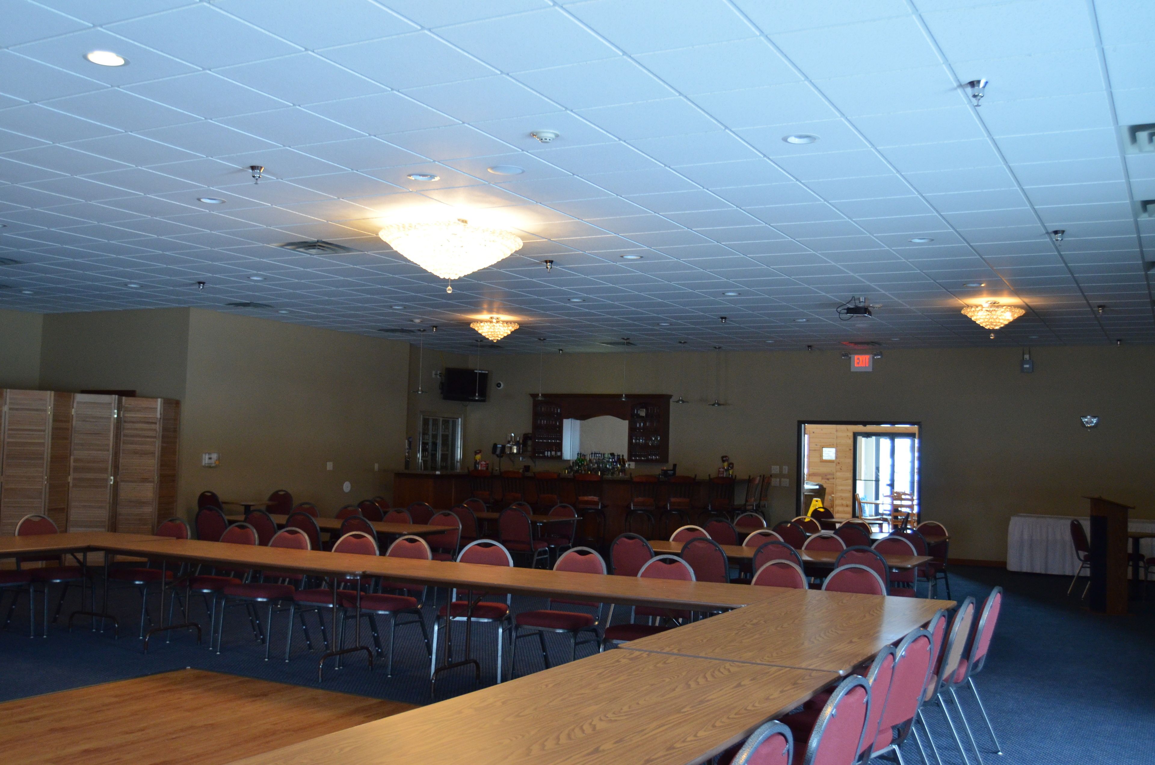 A conference room with a long table, multiple chairs, a bar area, and a chandelier.