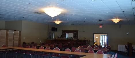 A conference room with a long table, multiple chairs, a bar area, and a chandelier.