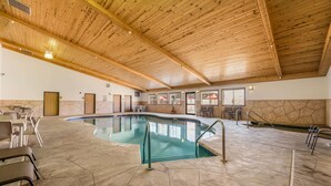 An indoor swimming pool with a wooden ceiling, stone walls, and seating areas. - Econo Lodge Rice Lake (Rice Lake)