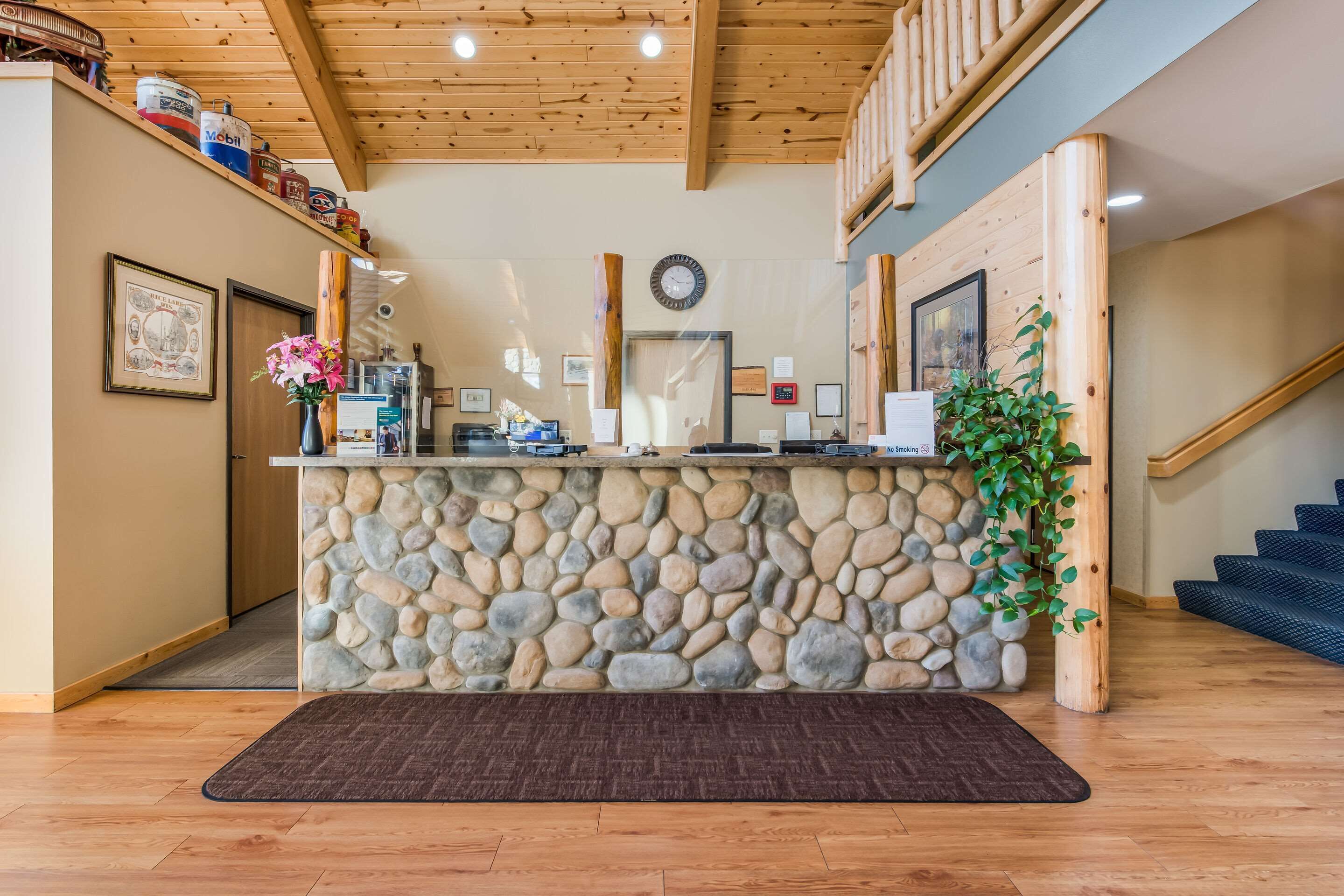 Un área de recepción con mostrador de piedra, techo de madera y una escalera.
