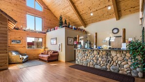 A wooden interior with a stone counter, a sofa, and a fireplace. - Econo Lodge Rice Lake (Rice Lake)
