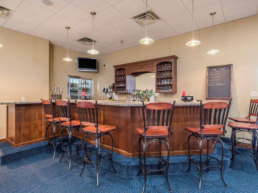 A bar area with a counter, bar stools, a wine list, and a television mounted on the wall.