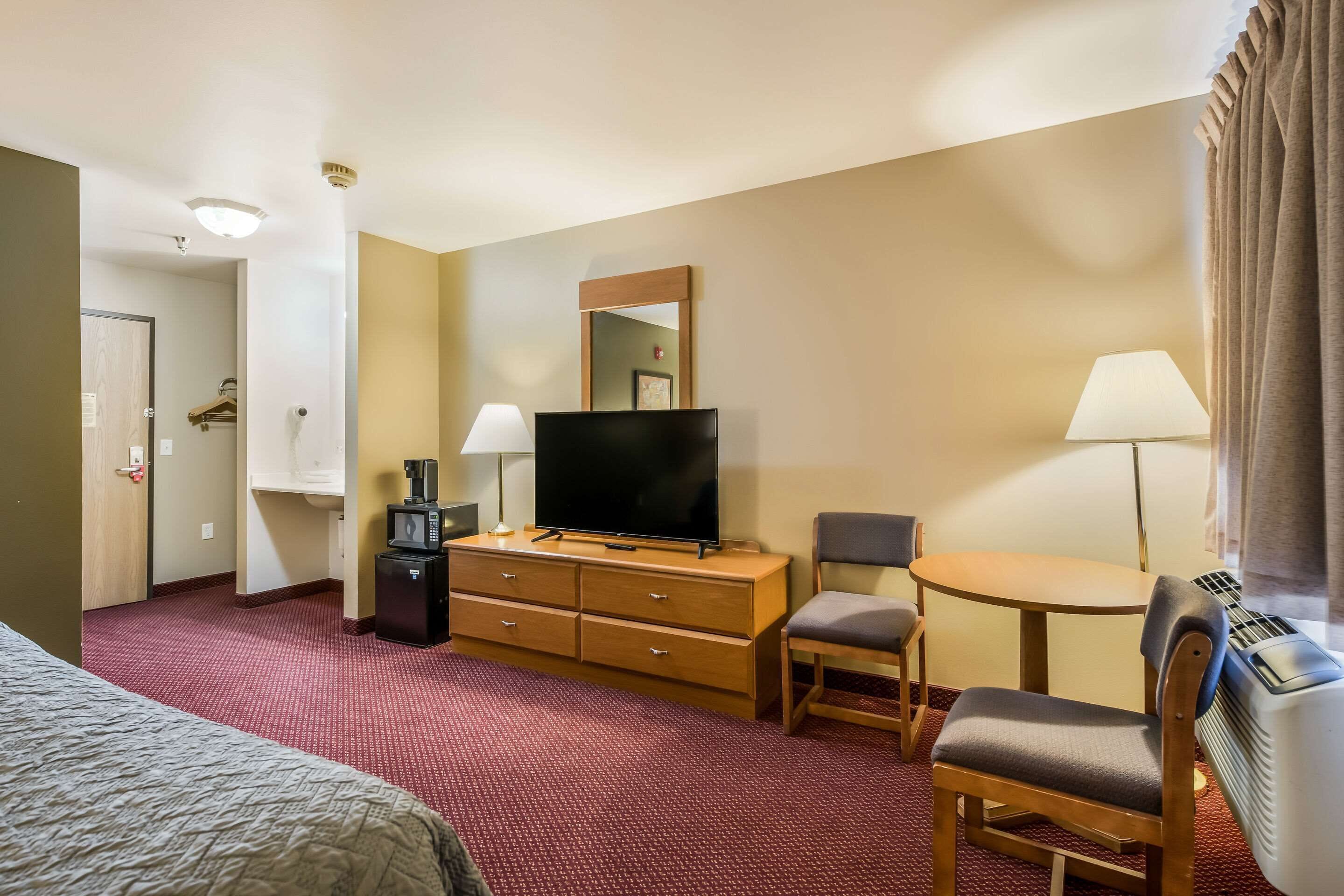 Een hotelkamer met een bed, een televisie, een kaptafel, een bureau met stoel en een verwarming.