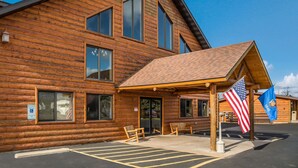A wooden lodge with a covered entrance, American and state flags, and a parking area with marked spaces. - Econo Lodge Rice Lake (Rice Lake)