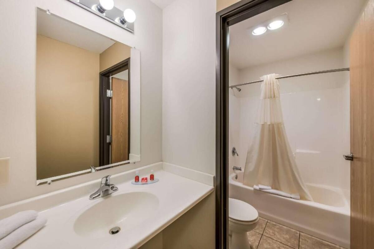 A bathroom with a sink, mirror, and shower area.