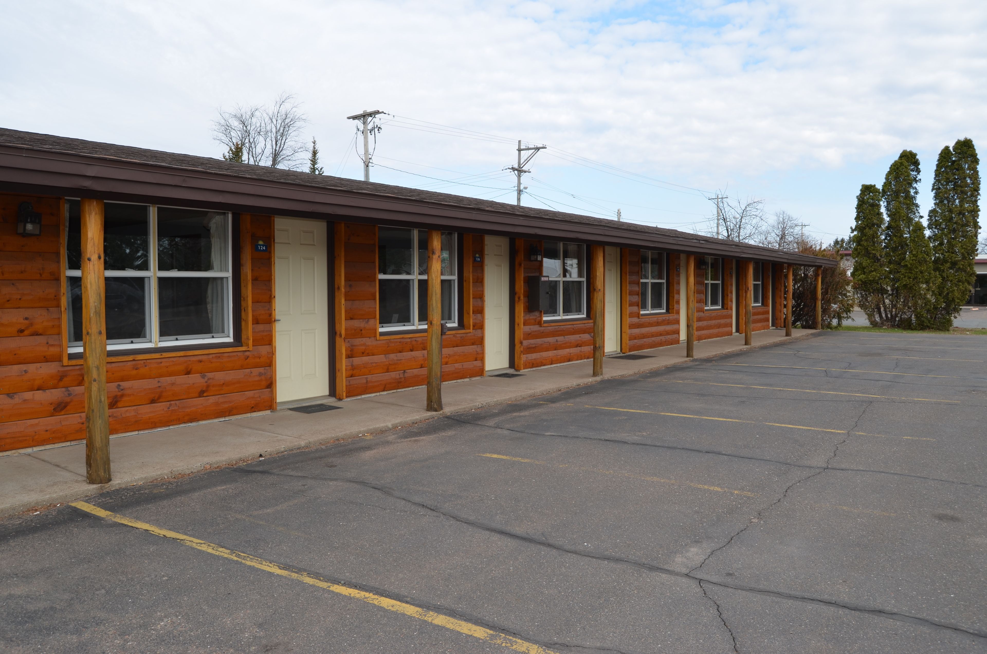 Une rangée de chambres de motel construites dans le style de chalets en rondins, avec un parking devant.