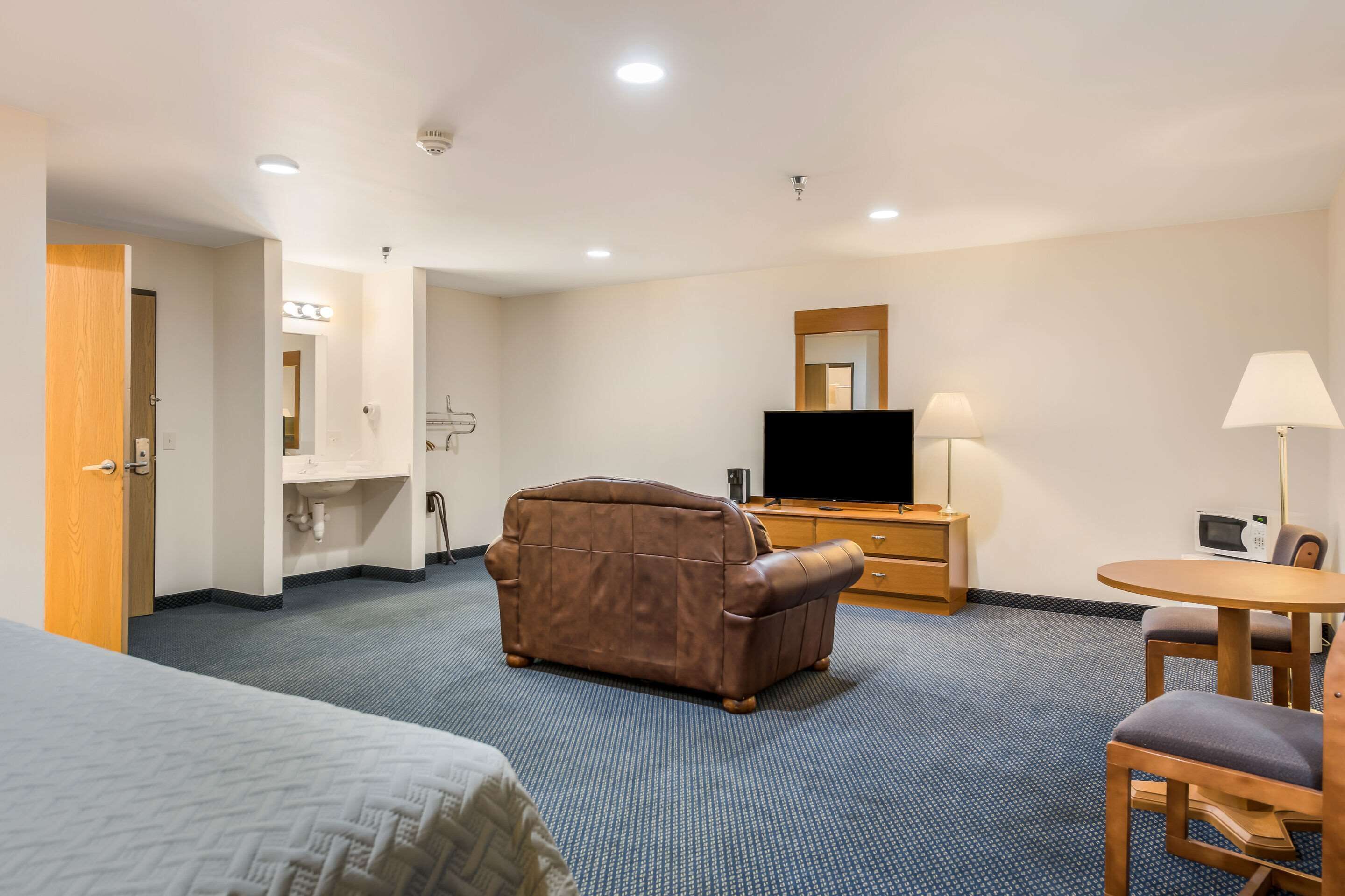 Habitación de hotel con cama, sofá, escritorio con televisor, lámpara y silla.