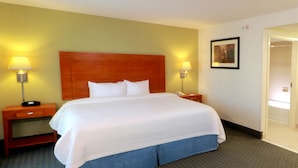Een hotelkamer met een groot bed, twee nachtkastjes met lampen, een houten hoofdeinde en een vloerbedekking.
