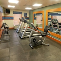 A gym with treadmills, elliptical machines, and a mirrored wall.