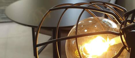 A modern interior with a spherical light fixture encased in a metal frame, a round table, and a sofa with a cushion.