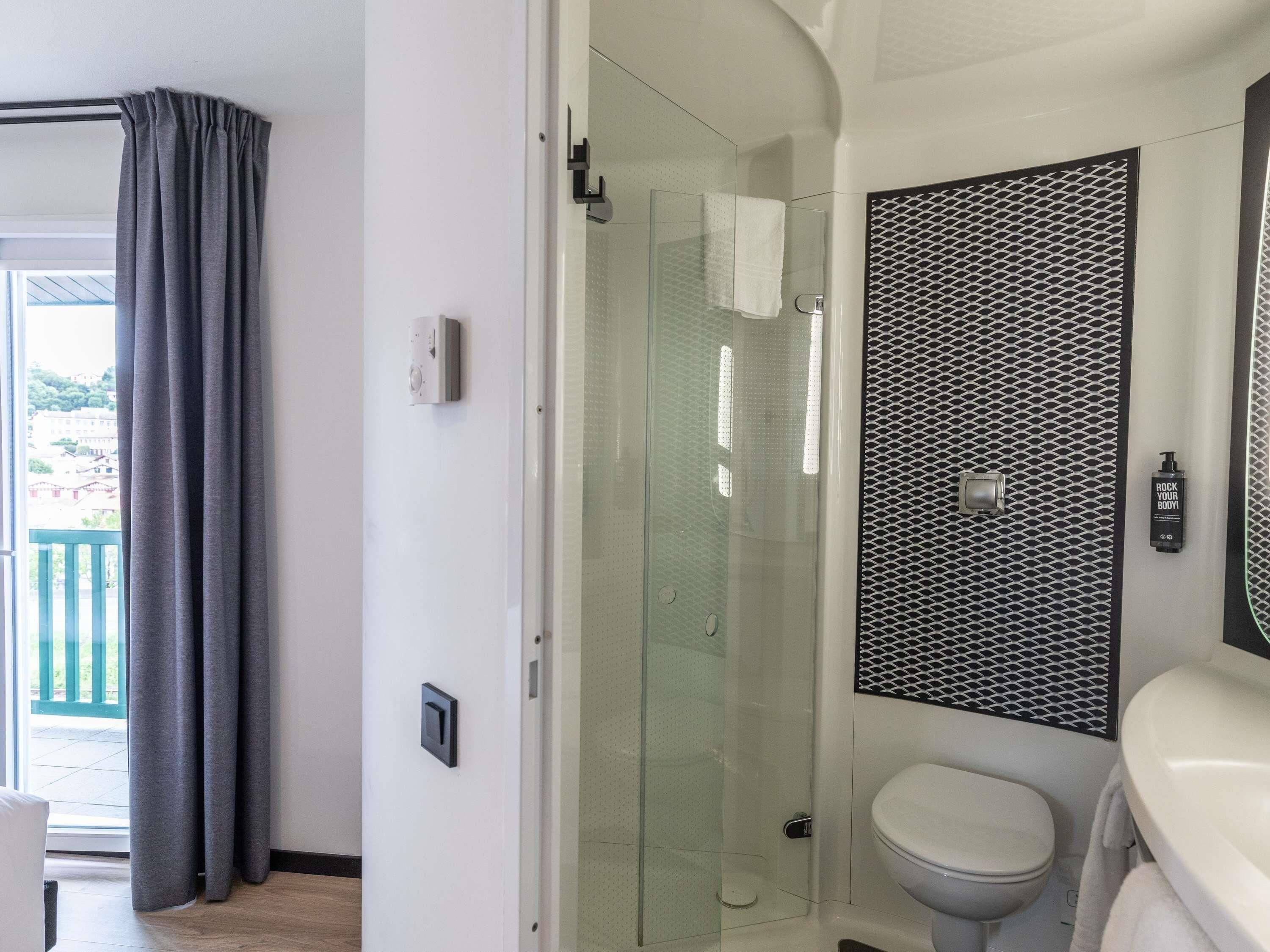 Une salle de bain moderne avec une douche à parois de verre, des toilettes et un lavabo avec un miroir.