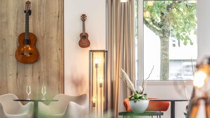 A modern interior with two guitars, a glass table, and a seating area. - ibis Ciboure St Jean De Luz Hotel (Ciboure)