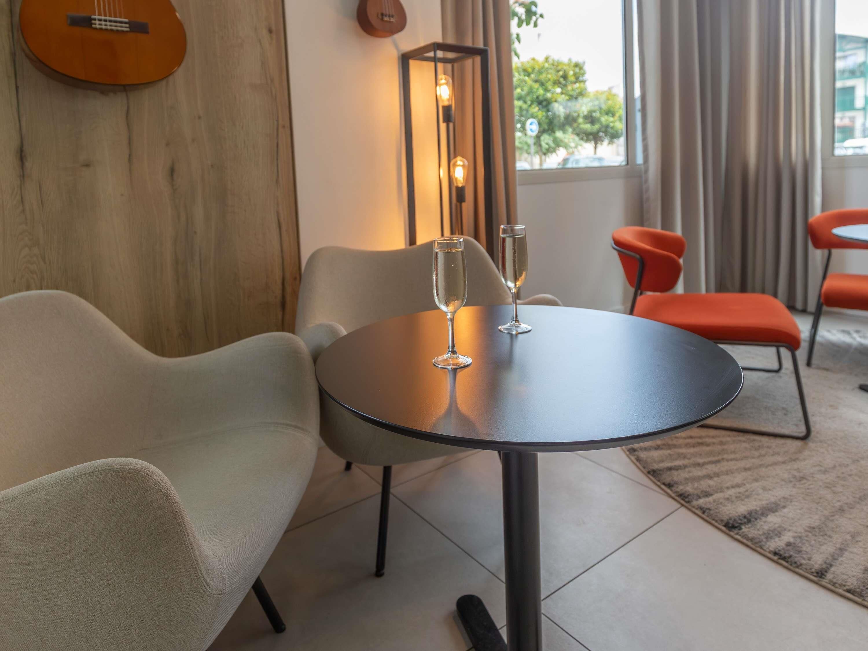 A modern room with a round table, two chairs, a guitar, and a floor lamp.