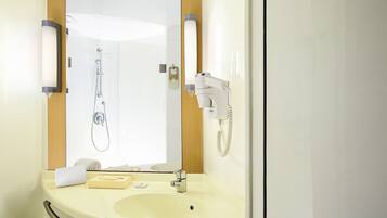 Een badkamer met een wastafel, spiegel, handdoekhouder en een haardroger.