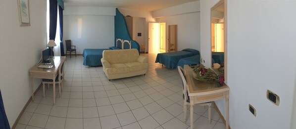 A living room with a sofa, a chair, a table, and a bed.