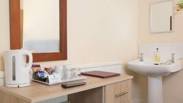 Un bagno con un mobile lavabo in legno, un lavandino bianco, uno specchio e una macchina da caffè.