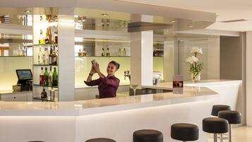 Un bar moderno con un cantinero, taburetes de bar y una variedad de botellas de licores.