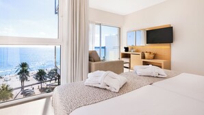 A hotel room with a large window, a bed, a desk, a chair, and a television. - CM Playa del Moro Hotel (Sant Llorenc des Cardassar)