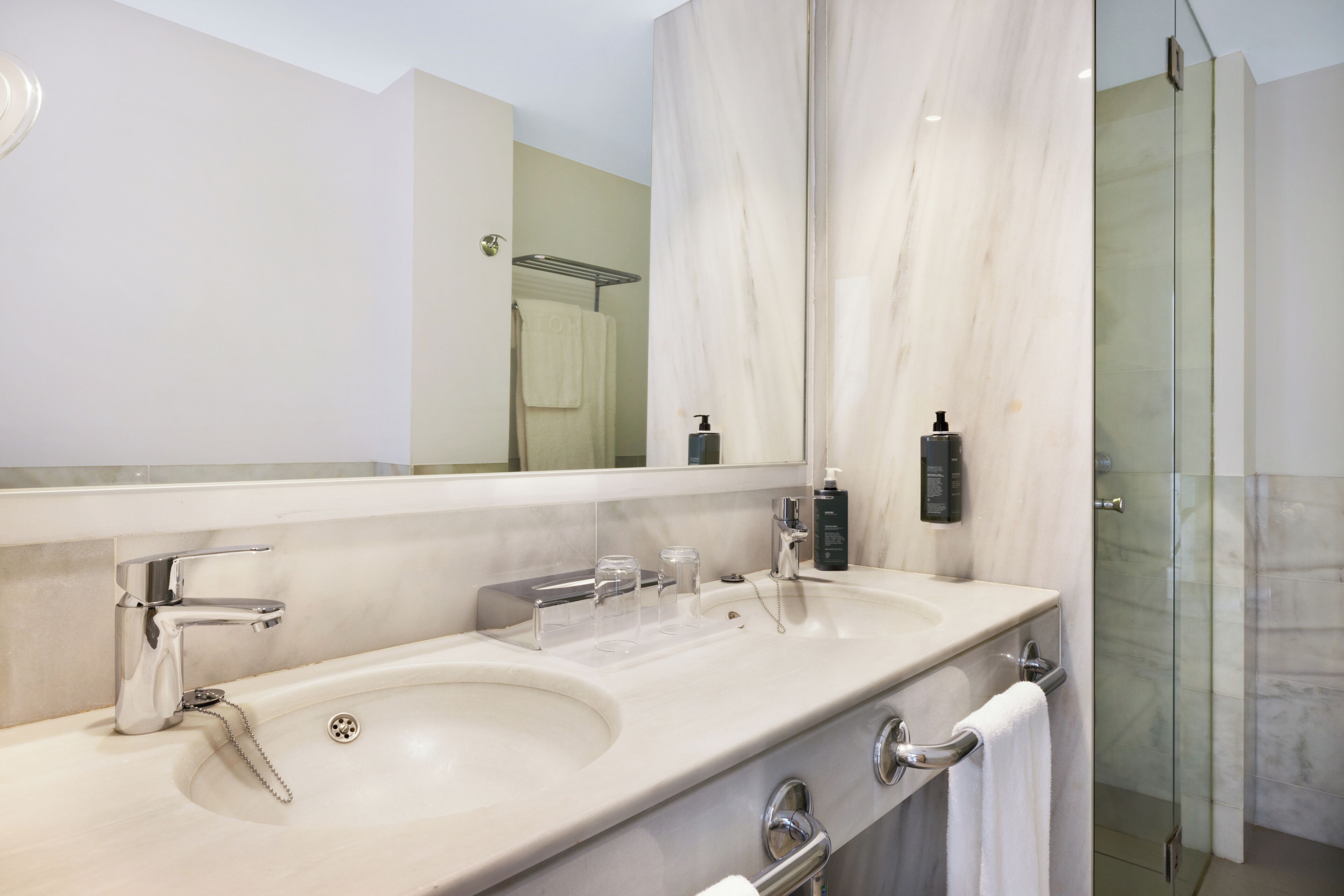 Un baño moderno con lavamanos doble, un espejo grande y una ducha con cerramiento de vidrio.