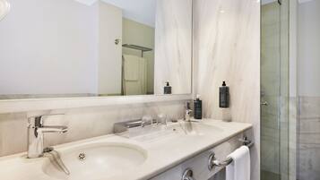 Un baño moderno con lavamanos doble, un espejo grande y una ducha con cerramiento de vidrio.
