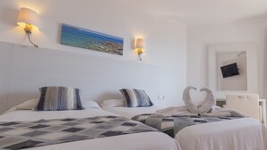 A hotel room with two beds, a painting of a beach, wall-mounted lamps, and a mirror with a black object on it. - R2 Verónica (Sant Llorenc des Cardassar)