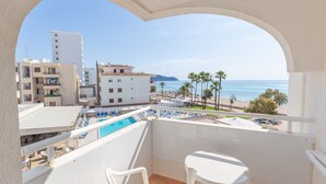 A balcony with a pool view, white furniture, and a clear view of the beach and ocean. - R2 Verónica (Sant Llorenc des Cardassar)