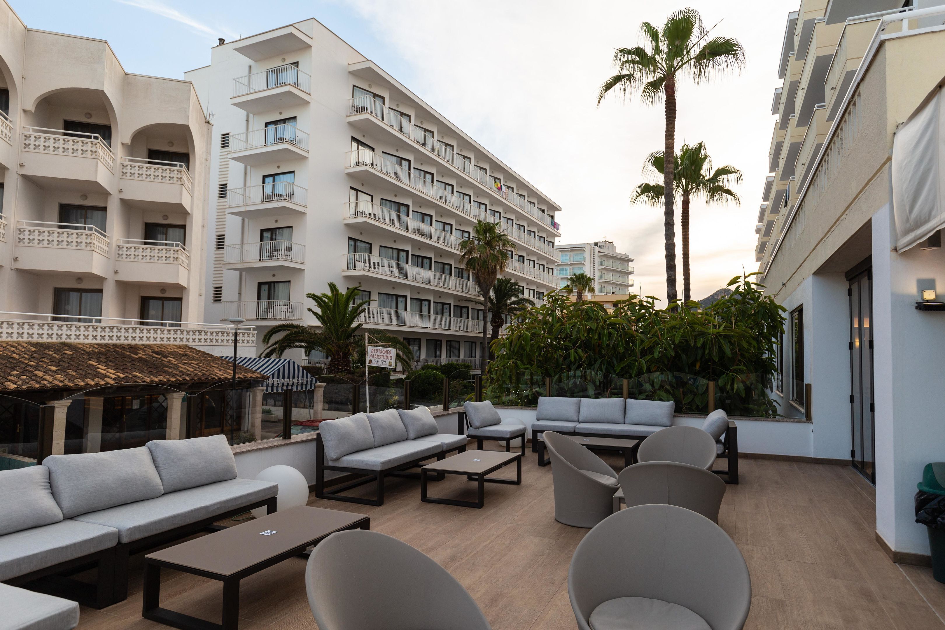 Een dakterras met terras, palmbomen en uitzicht op een hotelgebouw.