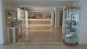 A modern reception area with a wooden reception desk, a glass display case with items, and a polished floor. - R2 Verónica (Sant Llorenc des Cardassar)