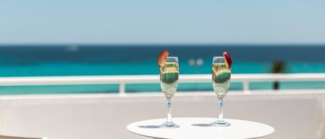 Two glasses of champagne on a white table with a view of the ocean.