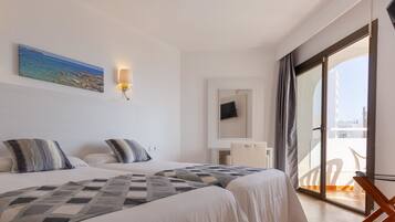 Habitación de hotel con dos camas, un cuadro de una playa, un televisor en la pared y un balcón con una silla.