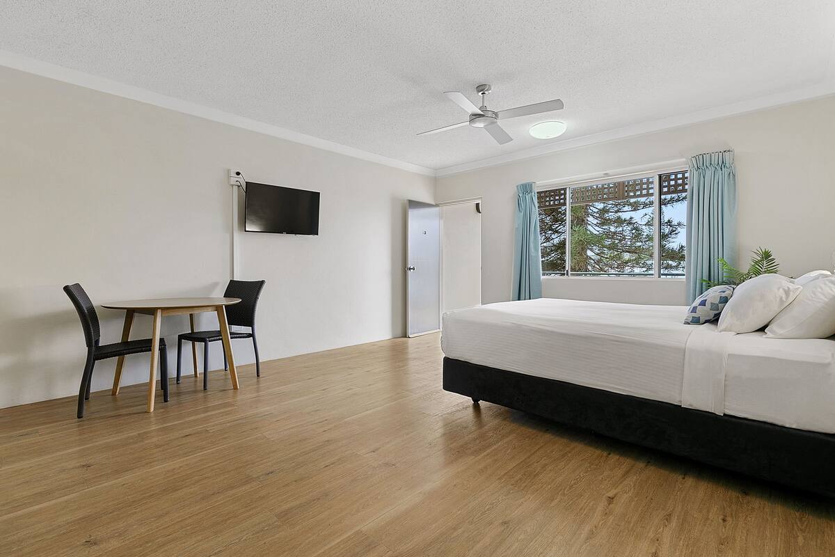 A bedroom with a bed, a desk, and a chair.