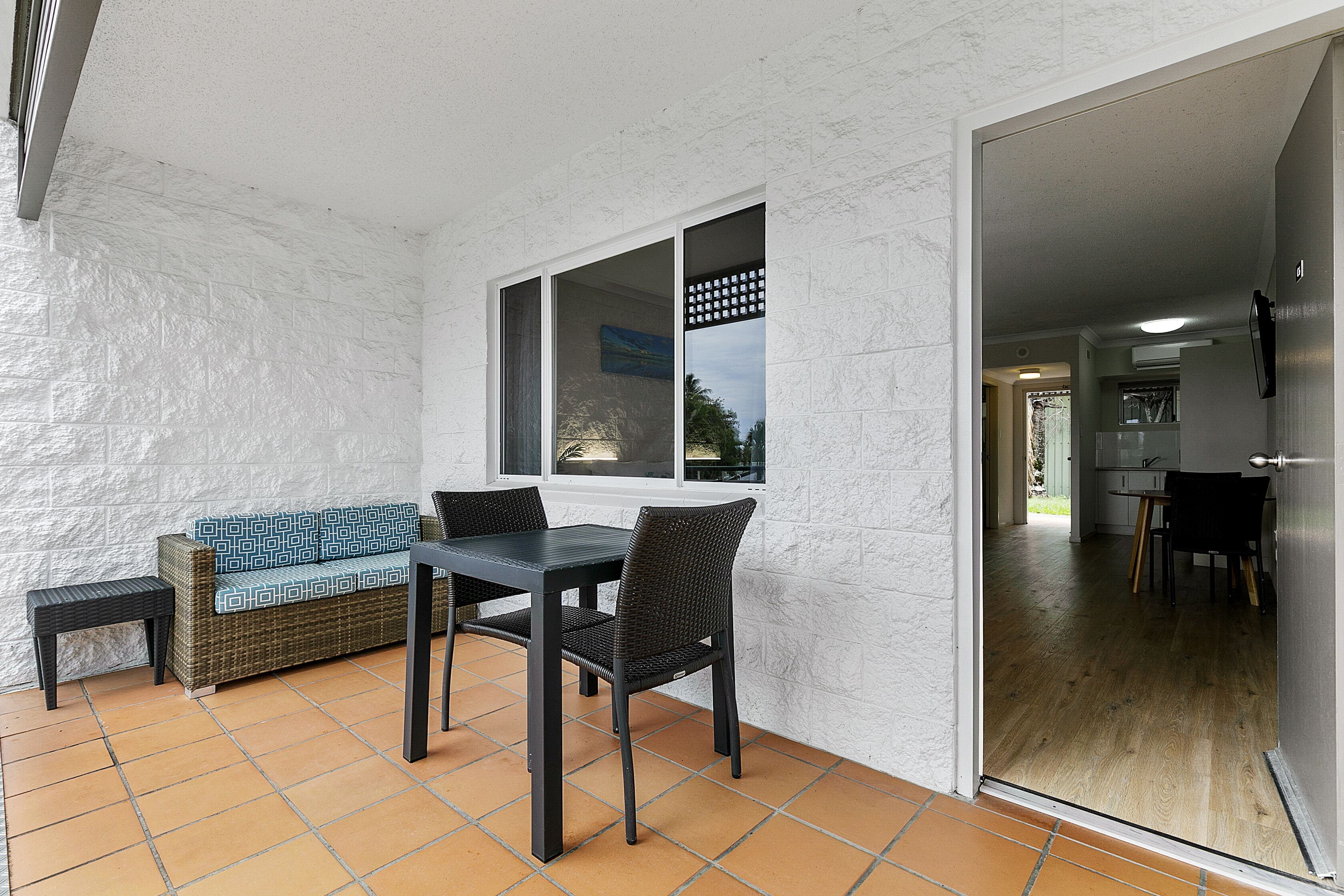 A patio area with a table and chairs, a wicker sofa, and a small side table.