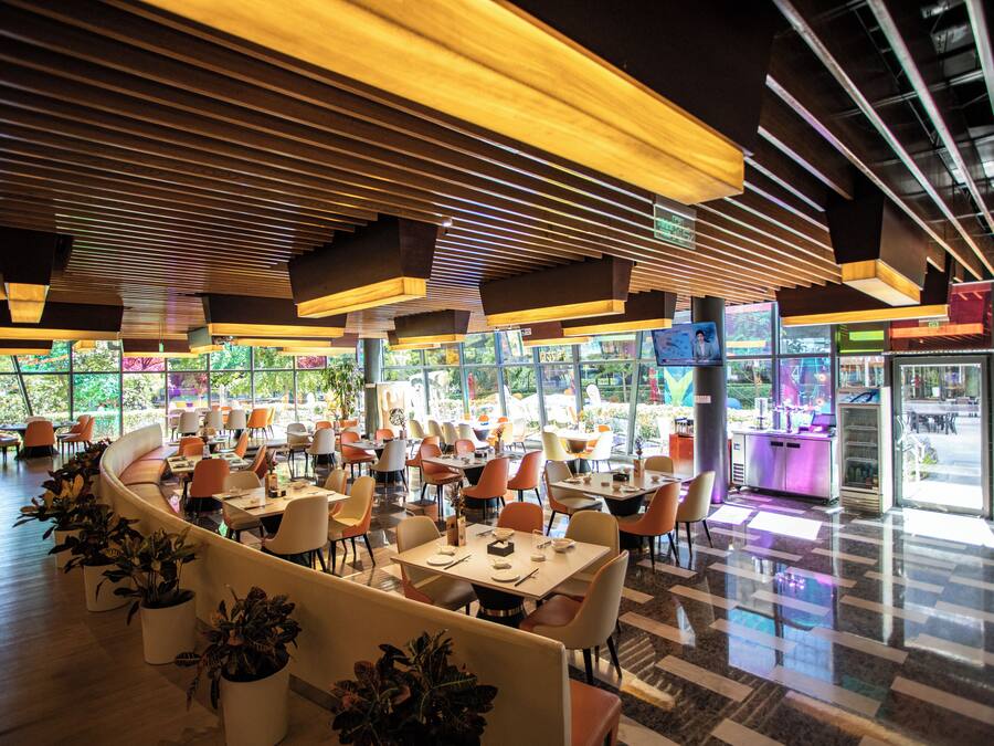 A modern restaurant with a curved seating area, multiple tables, and chairs.