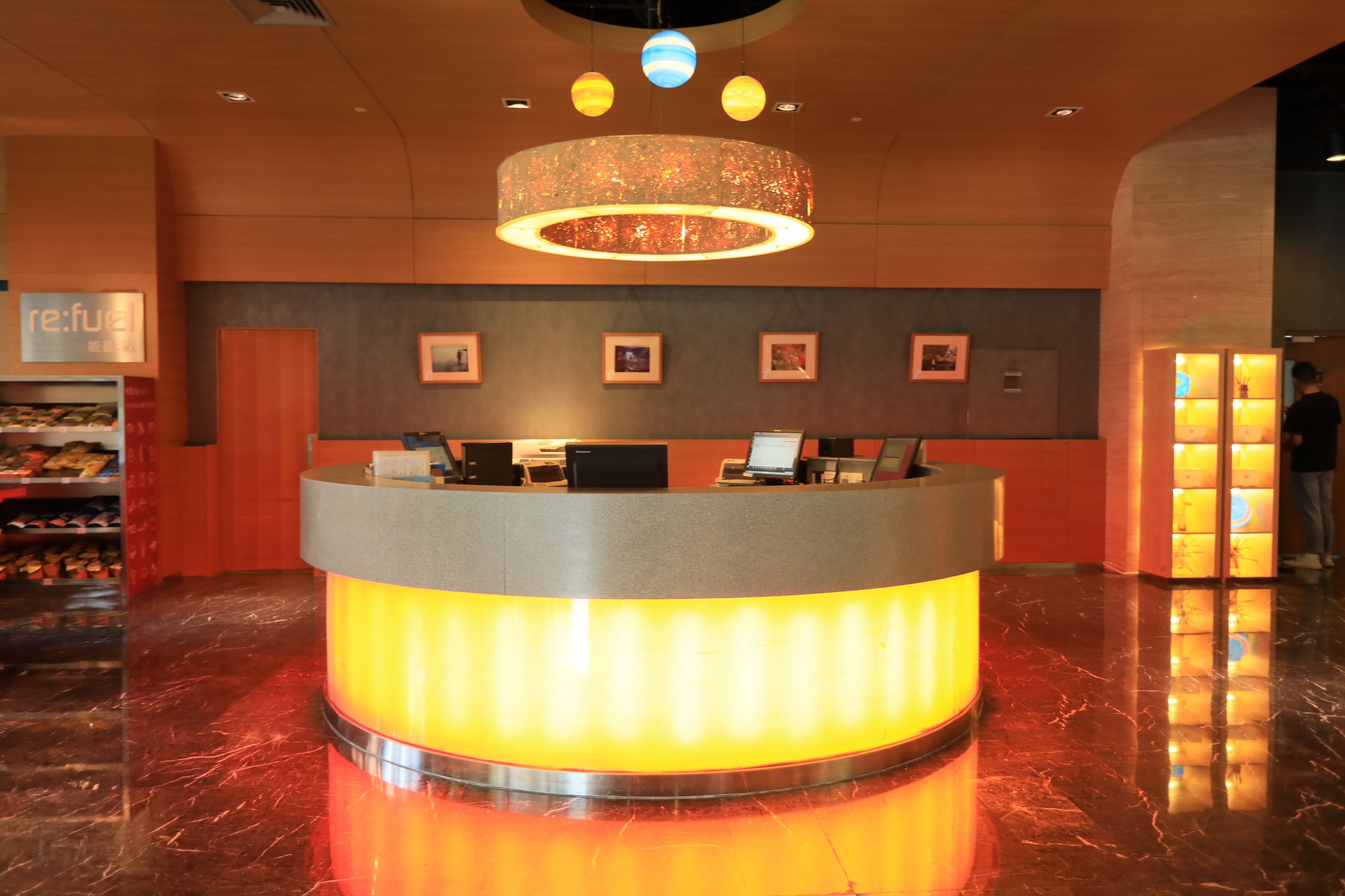 A reception desk with a circular design, a chandelier, and framed pictures on the wall.