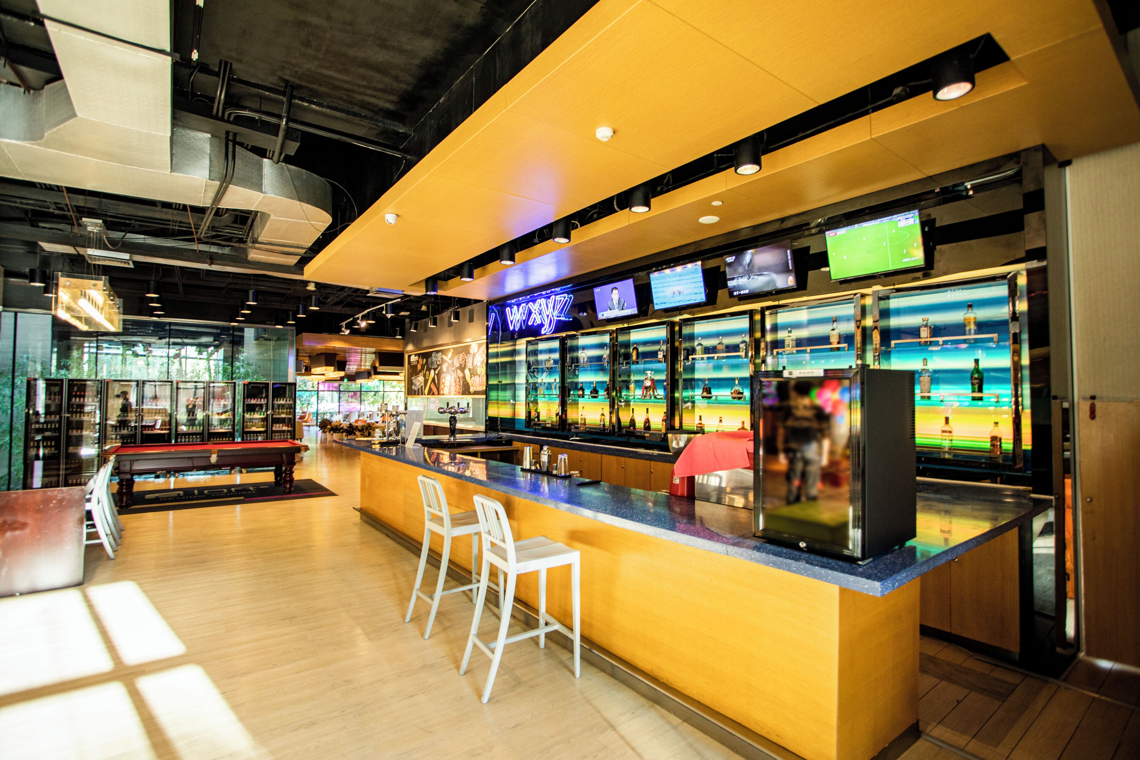 A bar area with a counter, stools, and a sports-themed decor.