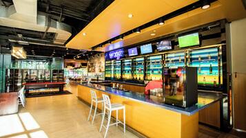 A bar area with a counter, stools, and a sports-themed decor.