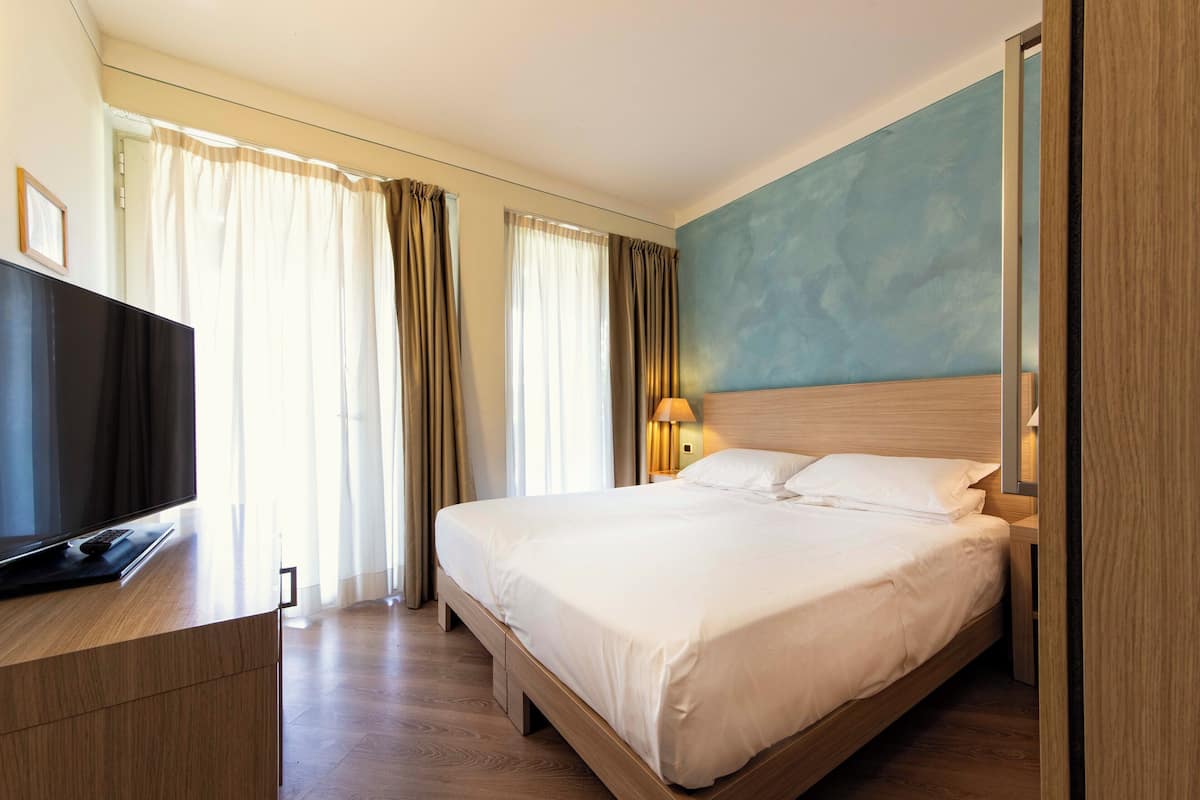 Una habitación de hotel con cama, televisor y cortinas.