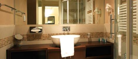 Une salle de bain avec un grand miroir, un lavabo, des toilettes et un espace douche.