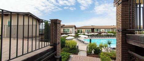 A hotel with a swimming pool, outdoor seating, and a view of the sky.