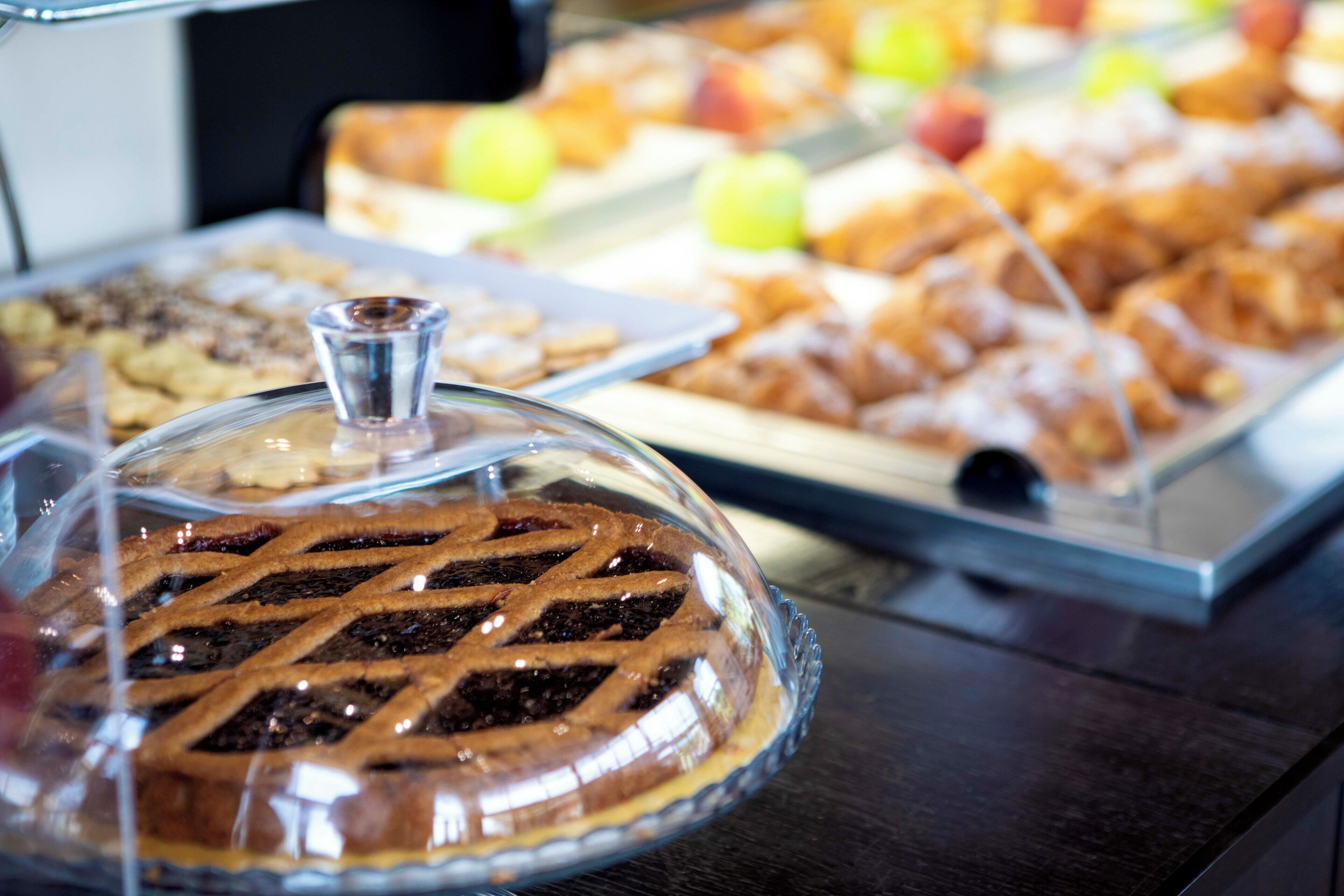 A buffet with various desserts including a covered pie, pastries, and fruit.