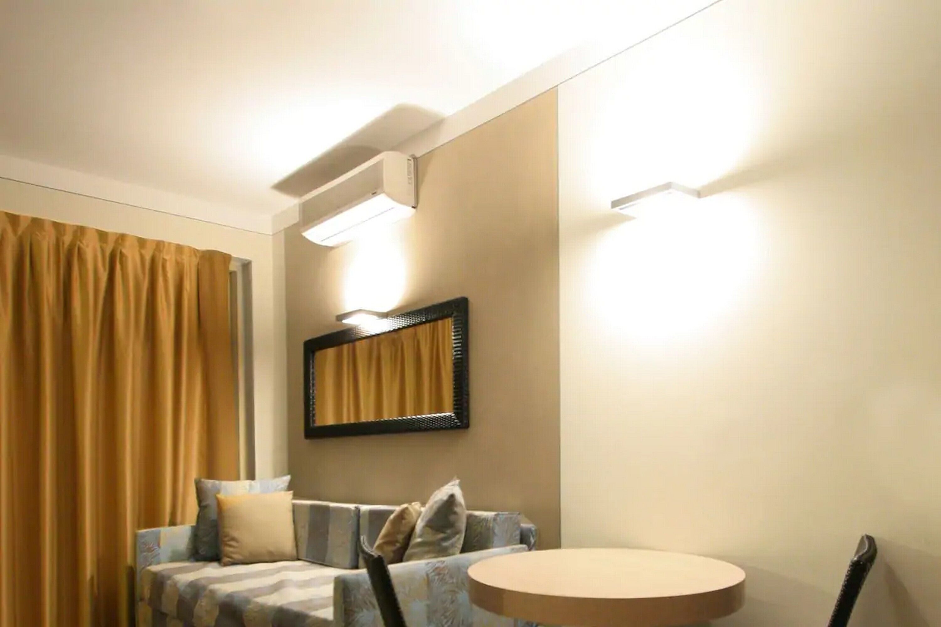 Une chambre d’hôtel avec un canapé, une table ronde et un miroir au mur.