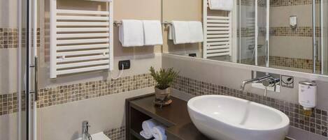 A modern bathroom with a large sink, a glass shower enclosure, and a mirror reflecting the space.